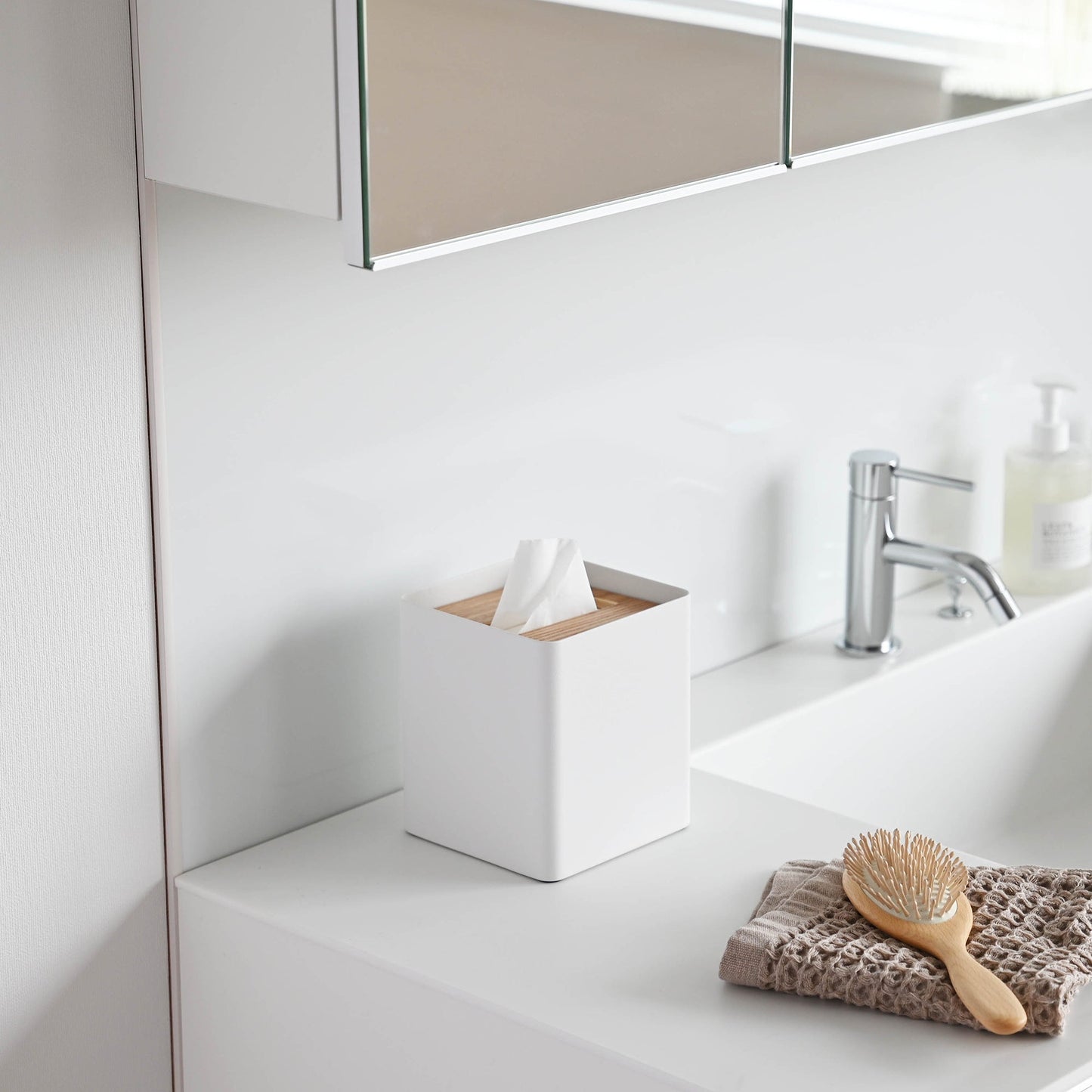 Side view of white Tissue Case on bathroom sink countertop by Yamazaki Home.