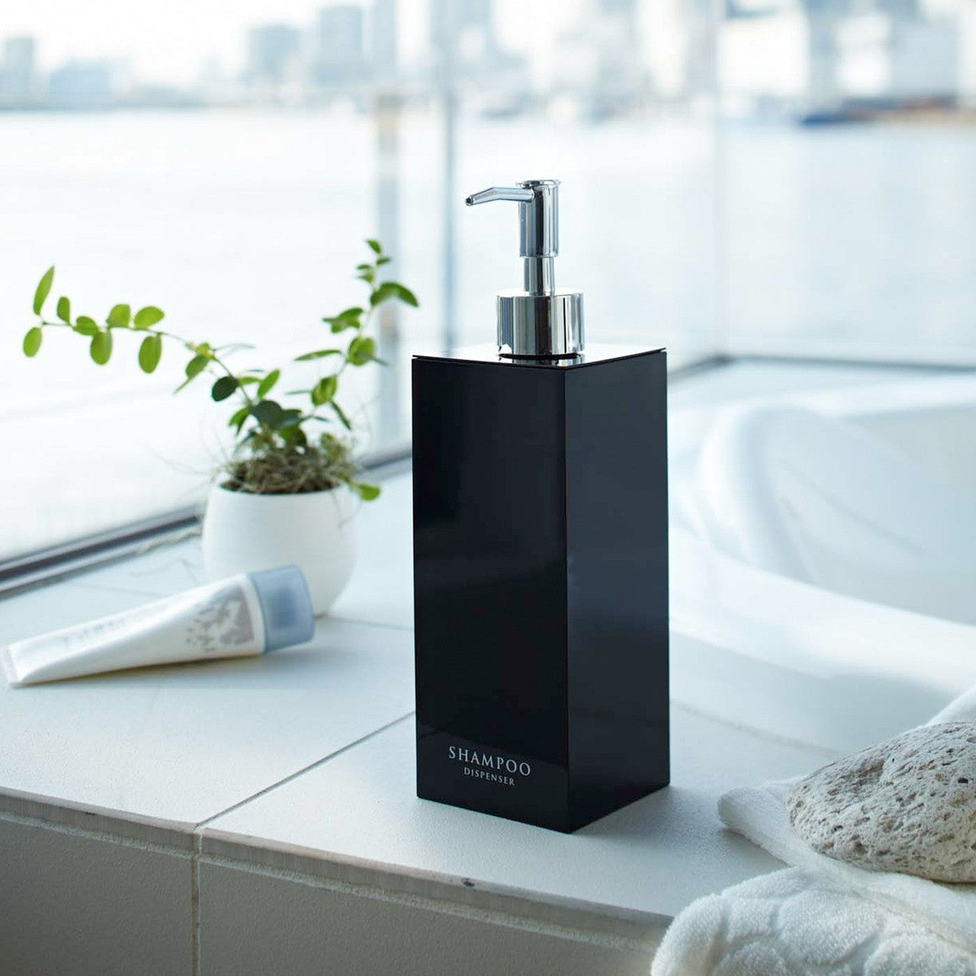 Black Yamazaki Home square shampoo dispenser by bathtub