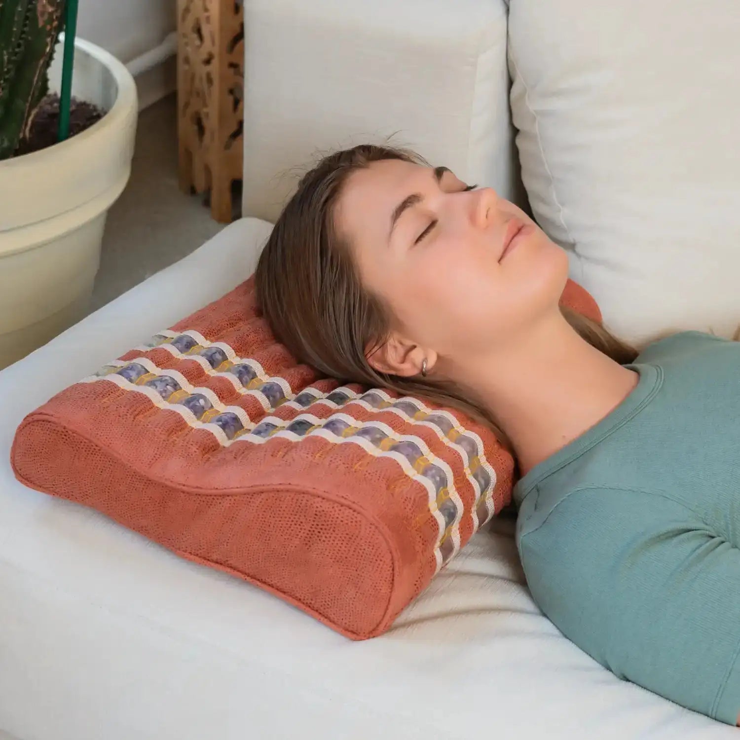 Woman using coral ergonomic pillow for neck support and relaxation