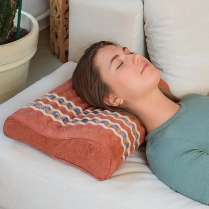 Woman using coral ergonomic pillow for neck support and relaxation