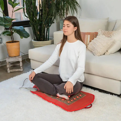 Woman using red HealthyLine PEMF infrared heating mat with LED lights for relaxation
