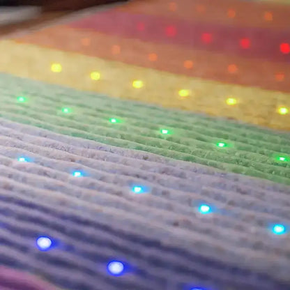 Macro texture of HealthyLine rainbow chakra mat fabric with embedded red to purple LED lights