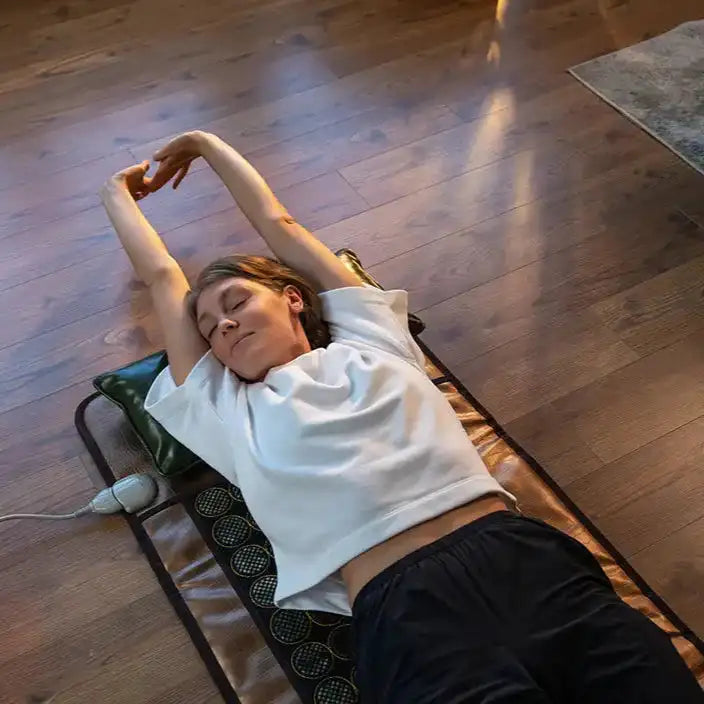Supine user stretching with HealthyLine infrared heating pad and remote