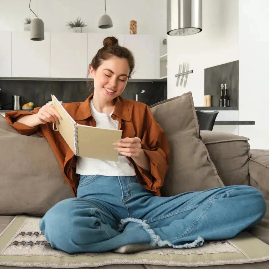 Woman meditating cross-legged on HealthyLine SOFT FAR infrared heating mat in home living room
