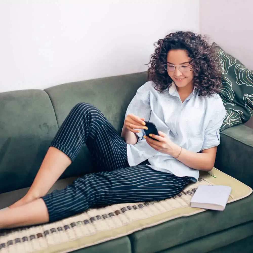 Woman relaxing on HealthyLine SOFT FAR infrared heating mat at home for wellness and comfort