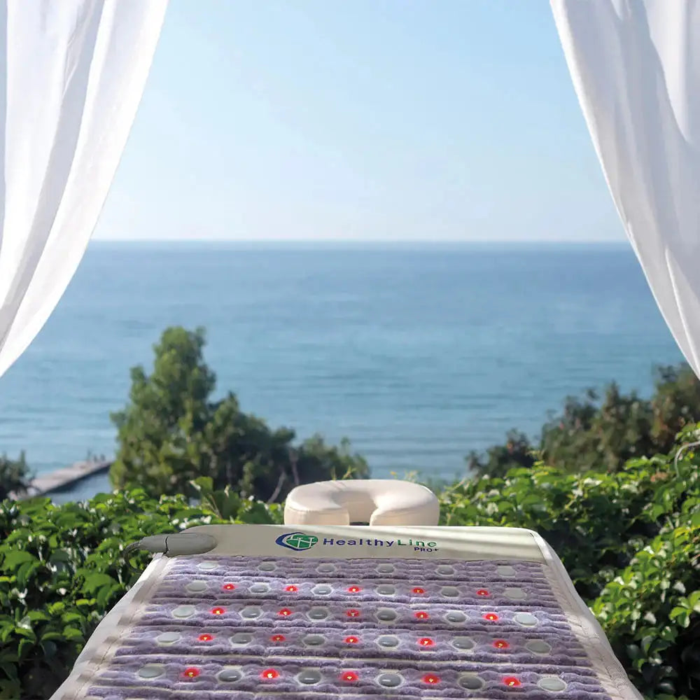 HealthyLine PRO+ PEMF mat outdoors on garden bed with red light therapy active