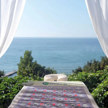 HealthyLine PRO+ PEMF mat outdoors on garden bed with red light therapy active