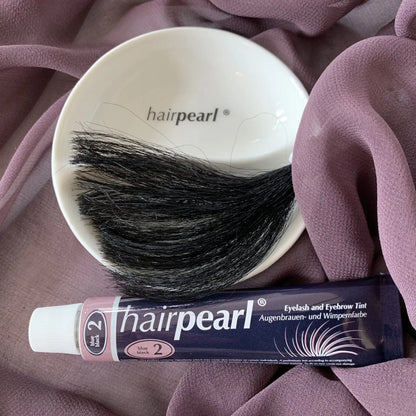 Hairpearl Blue Black Tint #2 tube with dark hair strands on purple fabric