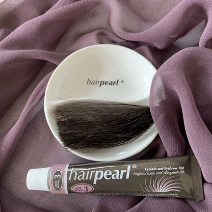 Hairpearl dark brown lash and brow tint flat lay with hair sample