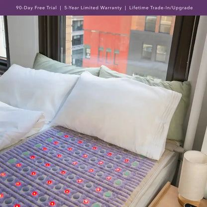 Purple HealthyLine TAJ PEMF mattress topper with red LED lights on bed with green bedding