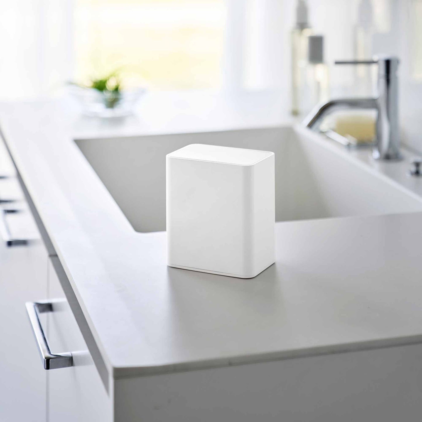 White cotton swab push-top case shown with the lid pushed down, concealing interior storage on a modern bathroom countertop.