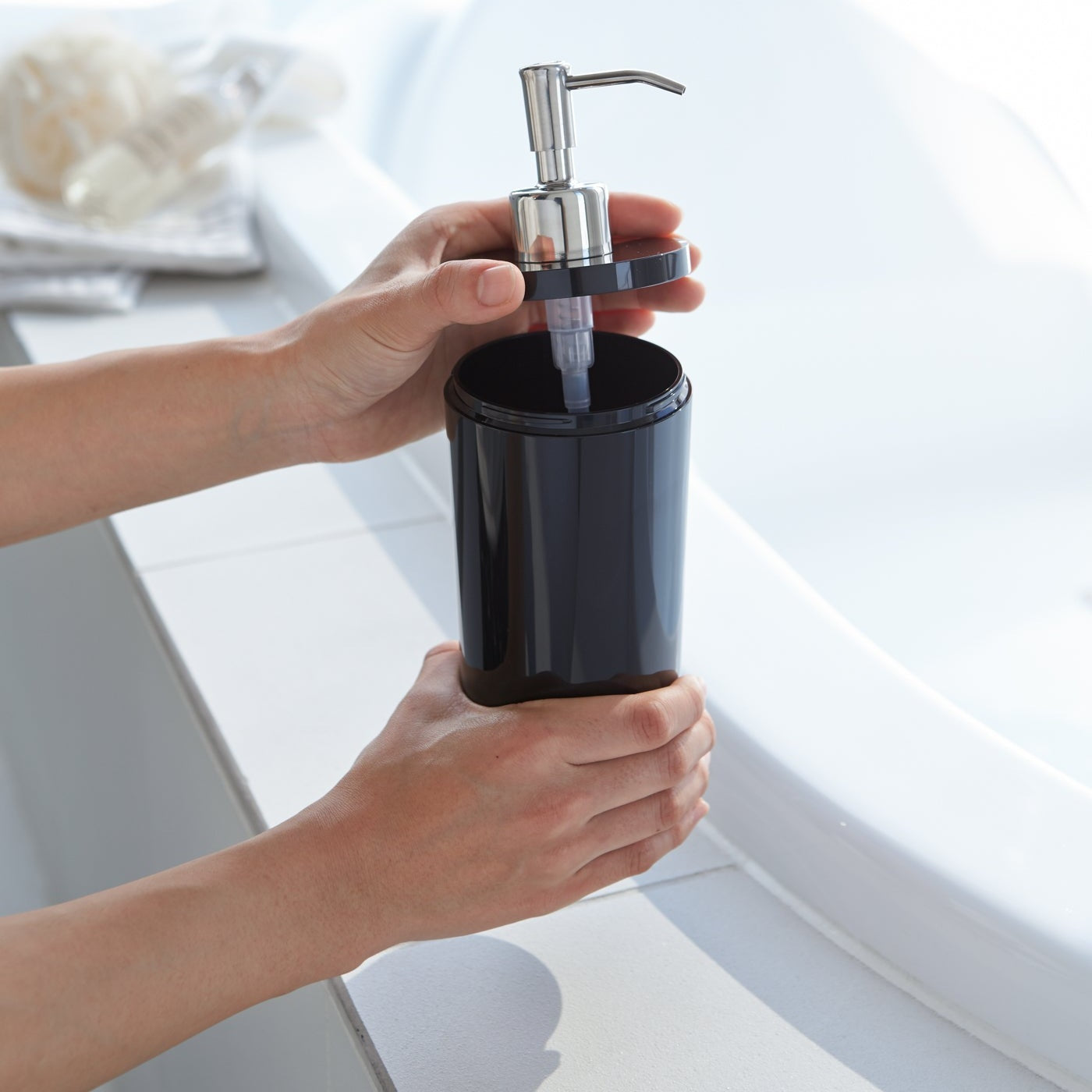Black Shampoo Dispenser with top off in bathroom by Yamazaki Home.