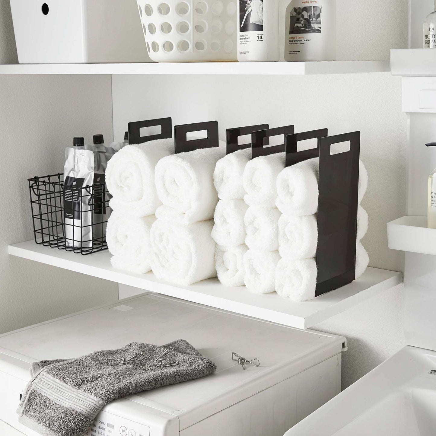 Black Towel Storage Organziers holding towels on laundry room shelf by Yamazaki Home.