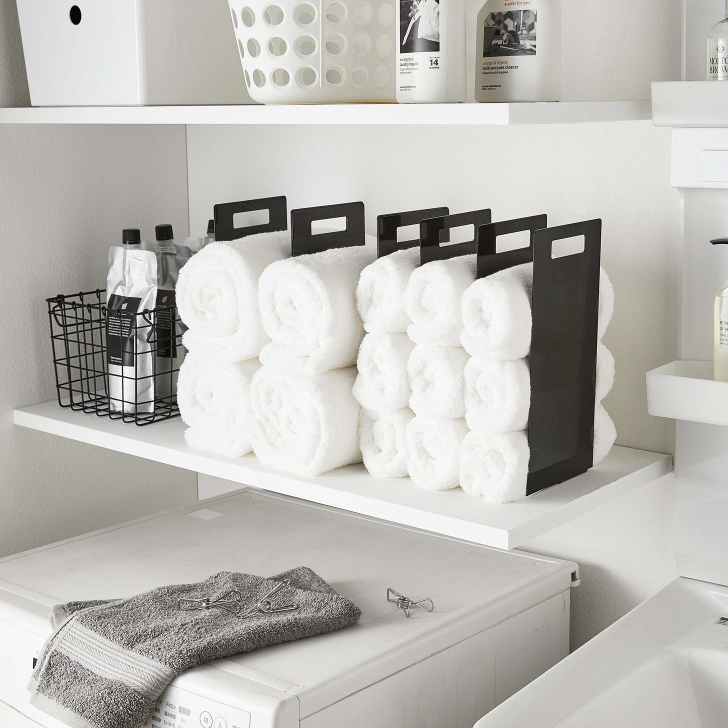 Black Towel Storage Organziers holding towels on laundry room shelf by Yamazaki Home.