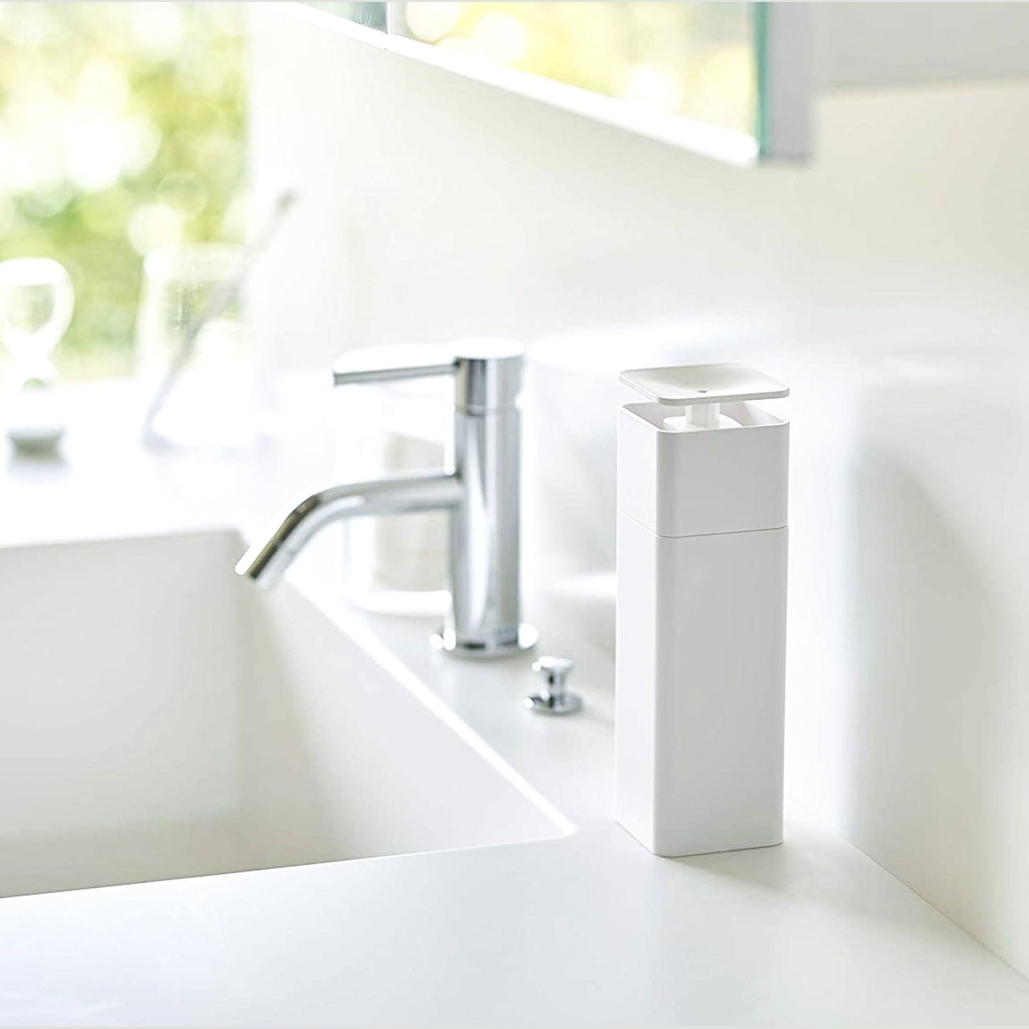 White One-Handed Push Soap Dispenser on bathroom sink counter by Yamazaki Home.