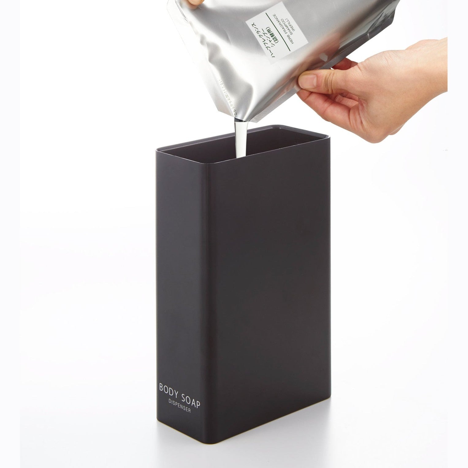 Black Body Soap Dispenser filled with soap on white background by Yamazaki Home.