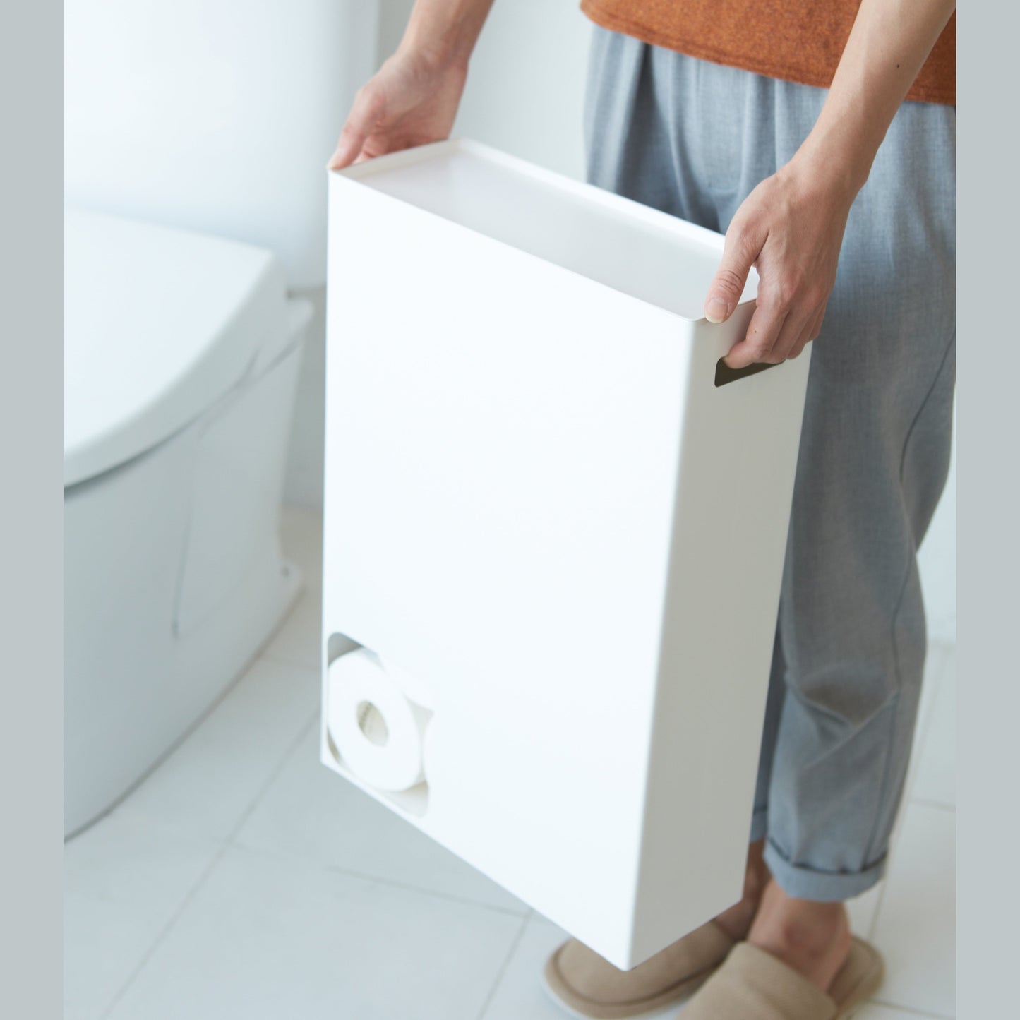 Front view of white Toilet Paper Stocker carried by handles in bathroom by Yamazaki Home.