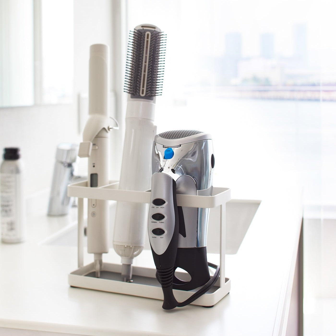White Hair Tool and Styling Accessory Organizer holding hot tools on bathroom counter by Yamazaki Home.