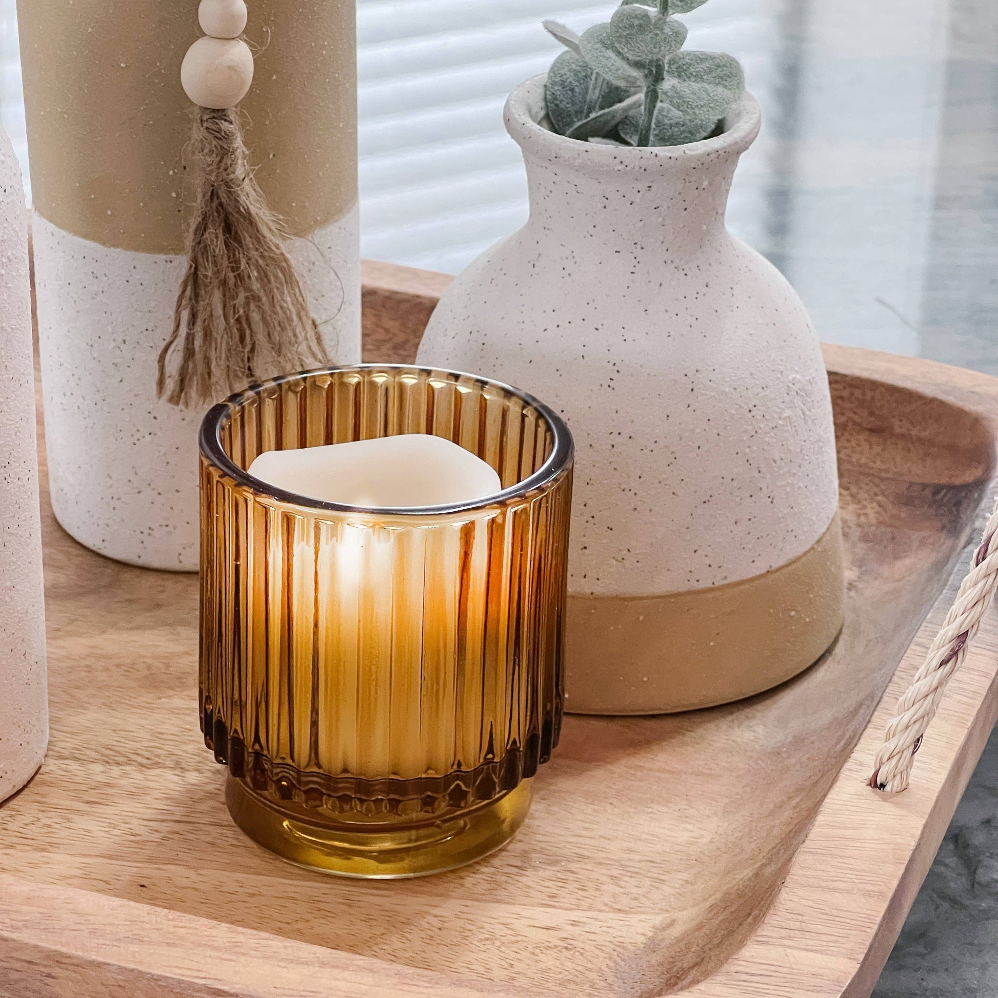 Lit amber glass votive holders on a styled tabletop