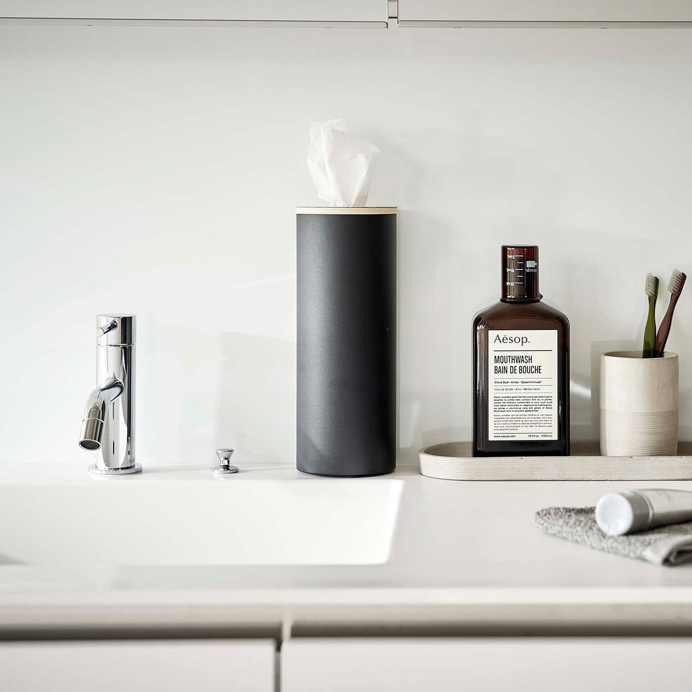 Large black Yamazaki Home Round Tissue Case on a bathroom sink counter