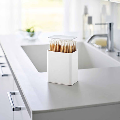 White Cotton Swab push-top case on a modern bathroom counter. QTips shown in the case.
