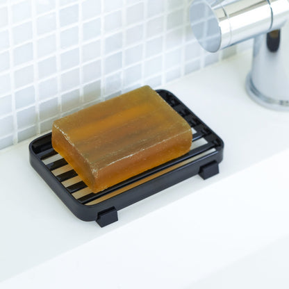 Black Slotted Soap Tray holding soap bar on sink counter by Yamazaki Home.