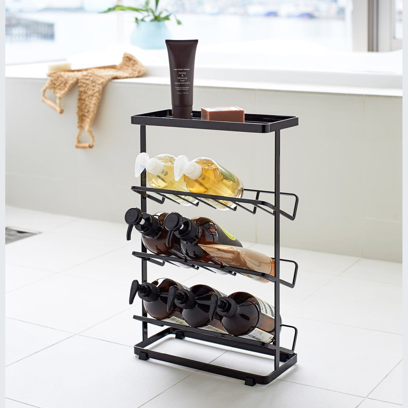 Black Freestanding Shower Caddy holding beauty products in bathroom by Yamazaki Home.