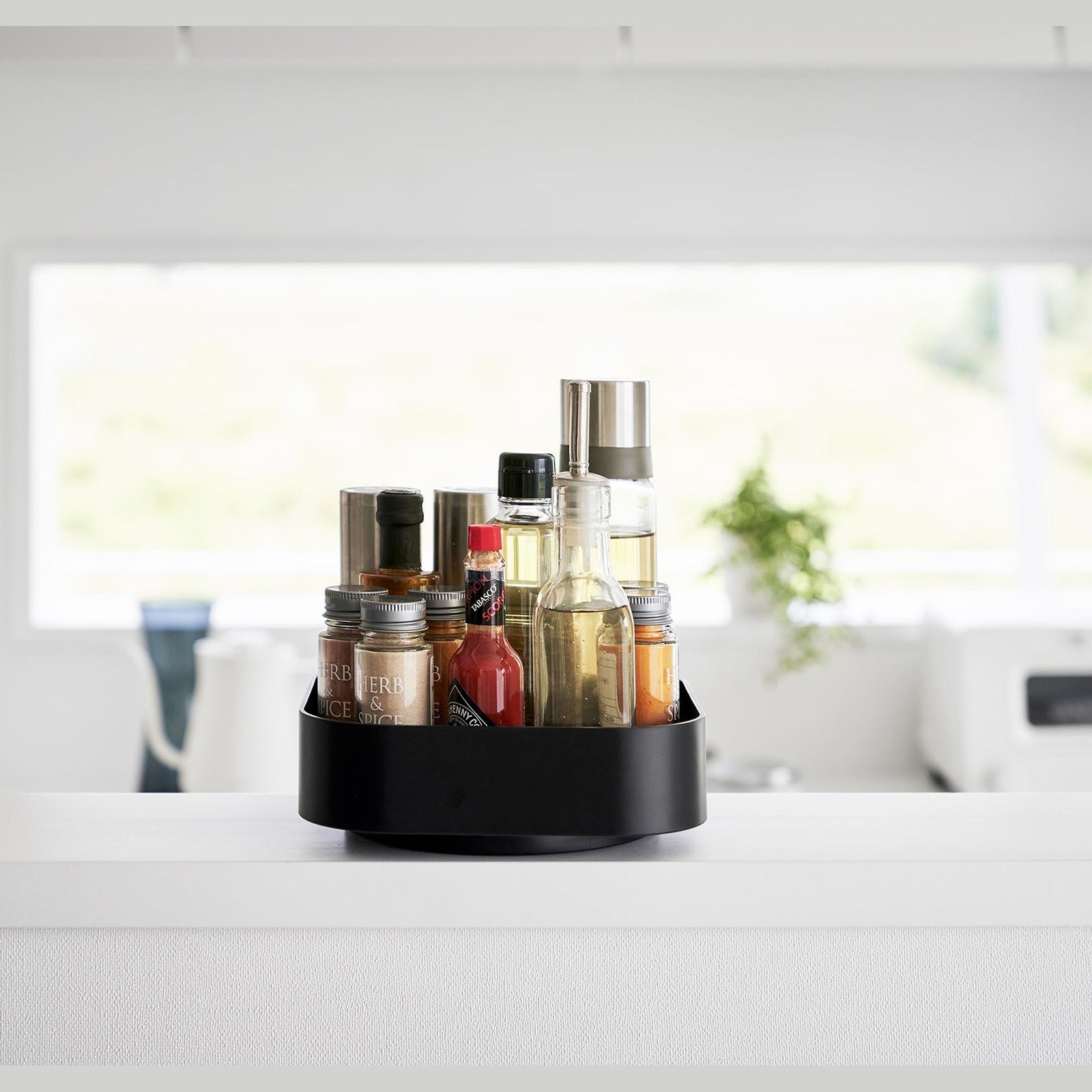 Front view of Black Yamazaki Home Rotating Storage Tray with spices and oil stored