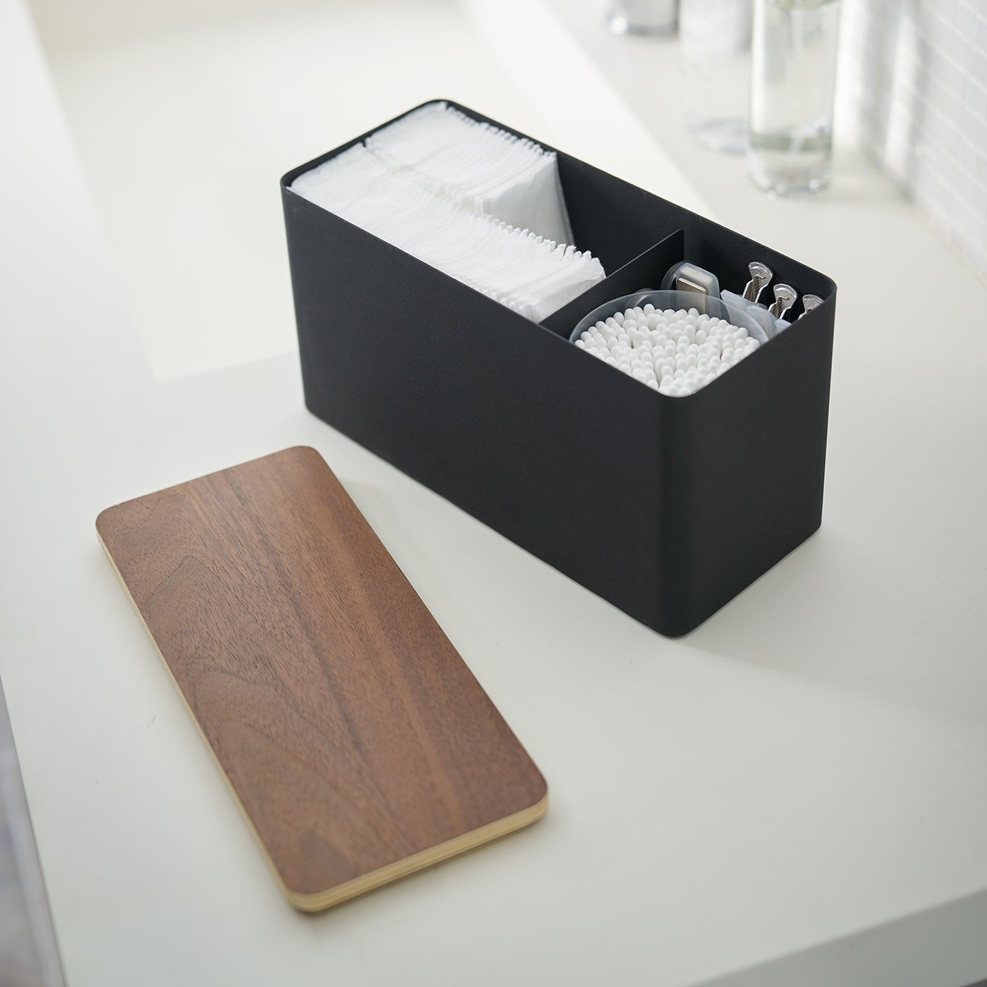 Black Countertop Organizer holding bathroom items with lid off on sink countertop by Yamazaki Home.