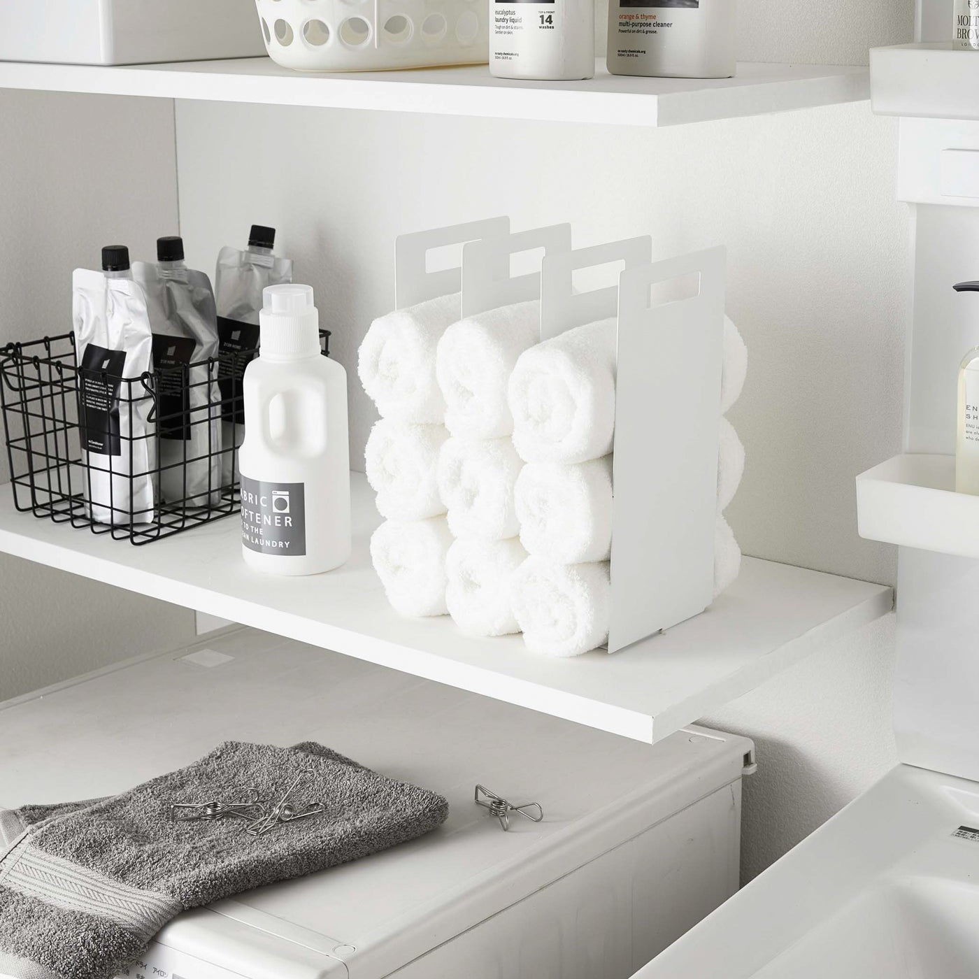 White Towel Storage Organizer displaying towels on laundry room shelf by Yamazaki Home.