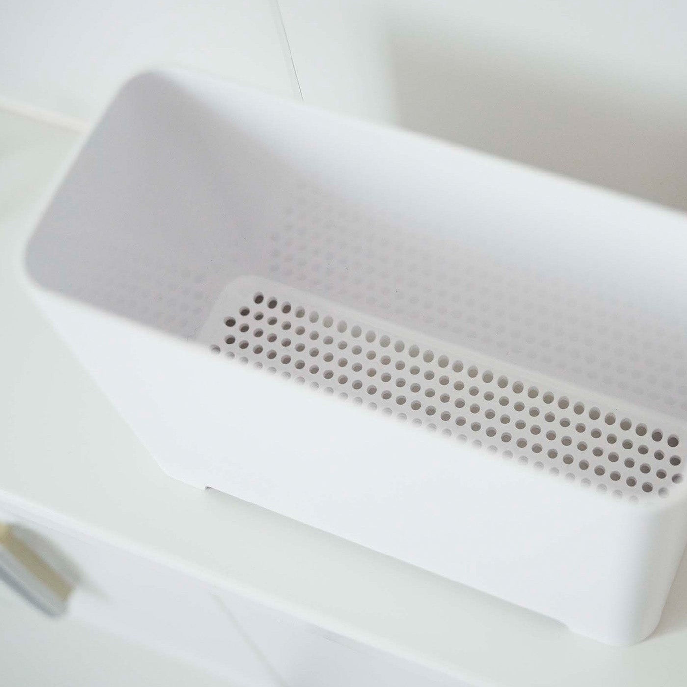Close up of draining holes of white Yamazaki Self-Draining Bathroom Organizer