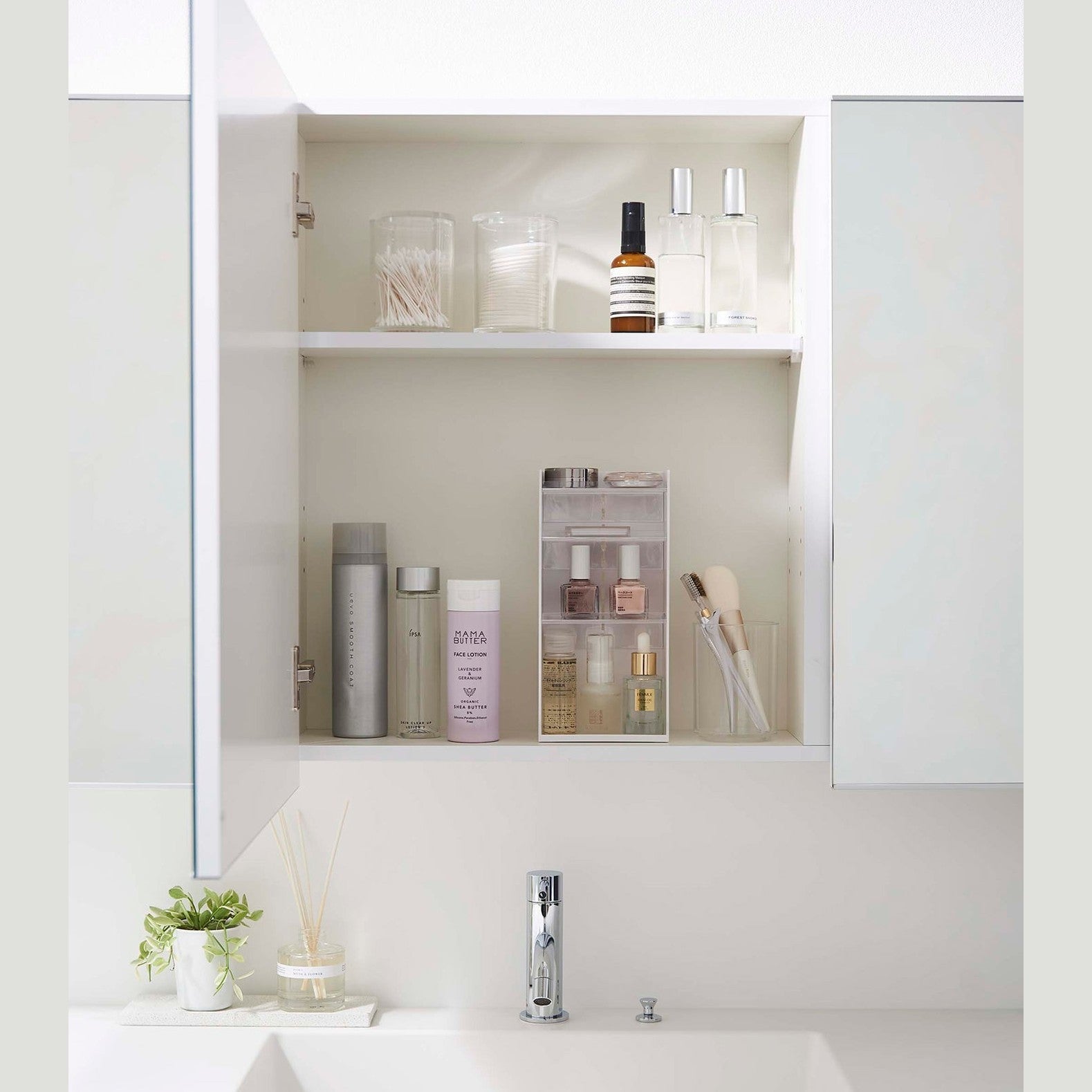 A white medicine cabinet is open to display the inside contents. Sunlight is focused on the right upper corner. Below is a bathroom sink.