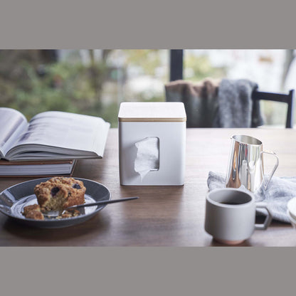 Front view of white toilet paper holder on tabletop by Yamazaki Home.