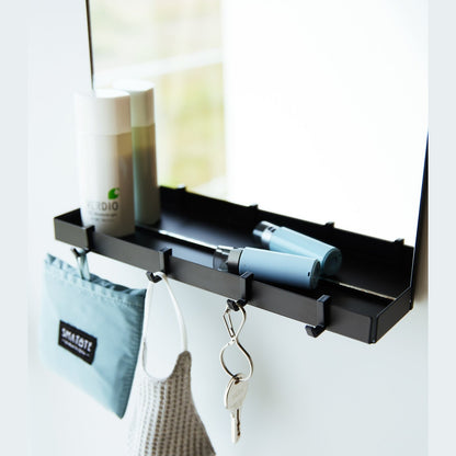 A black Yamazaki Magnetic Mirror With Storage Rack attached to a white door.