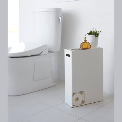 Side view of white Toilet Paper Stocker displaying phone and plant in bathroom by Yamazaki Home.
