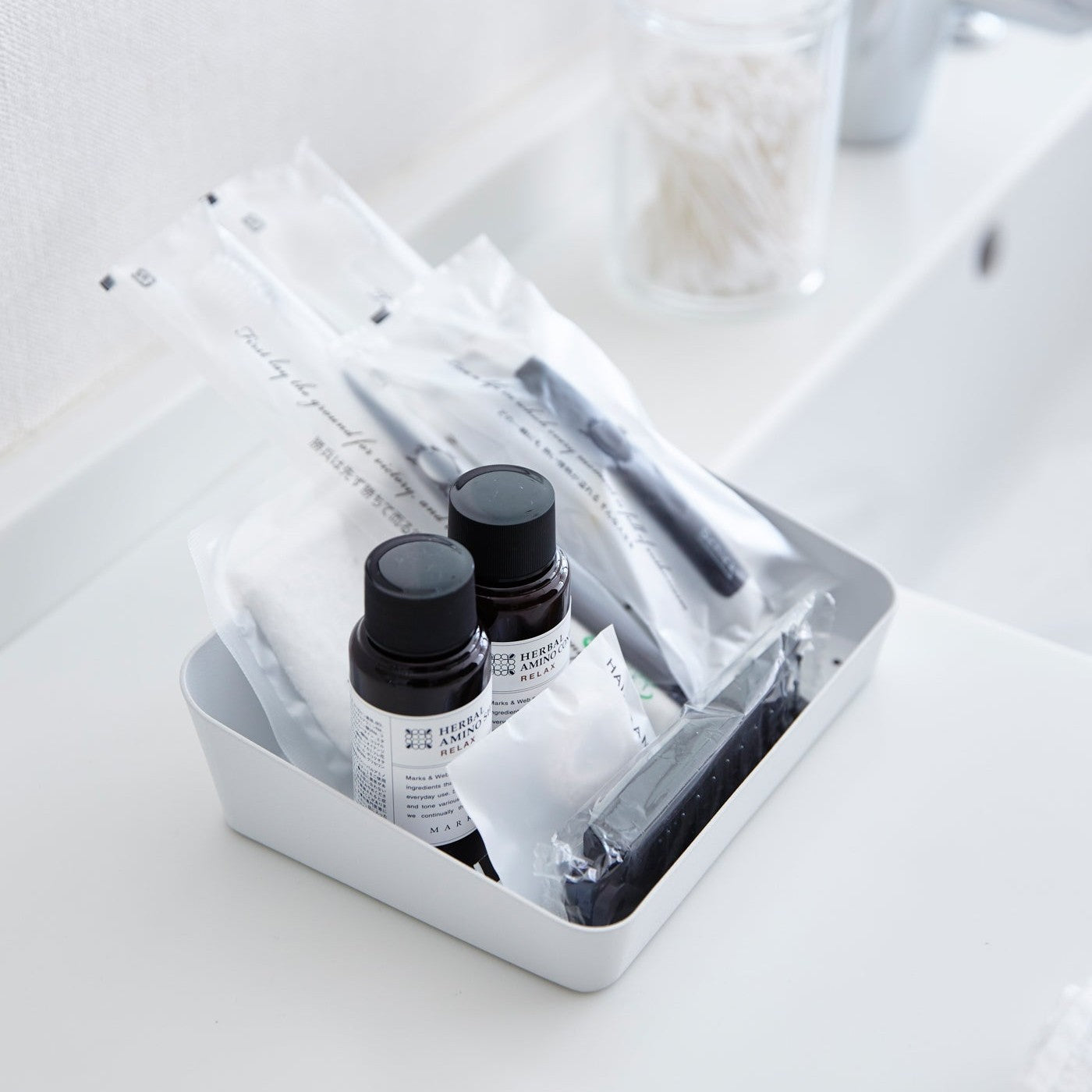 Aerial view of white Accessory Tray holding beauty products on bathroom sink counter by Yamazaki Home.
