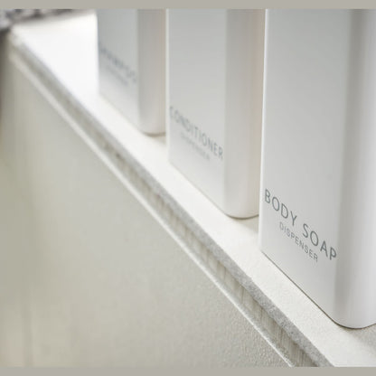 Close up bottom view of Yamazaki Home white Shampoo, Conditioner, and Body Soap dispensers.