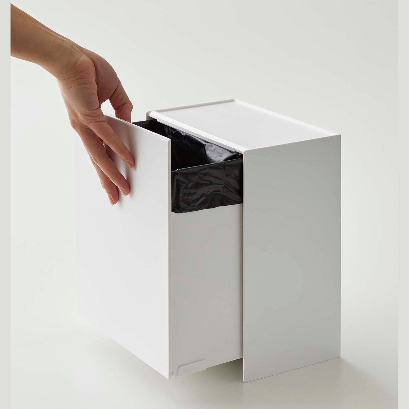 Person adjusting bin drawer on white Wall-Mount Storage on white background by Yamazaki Home.