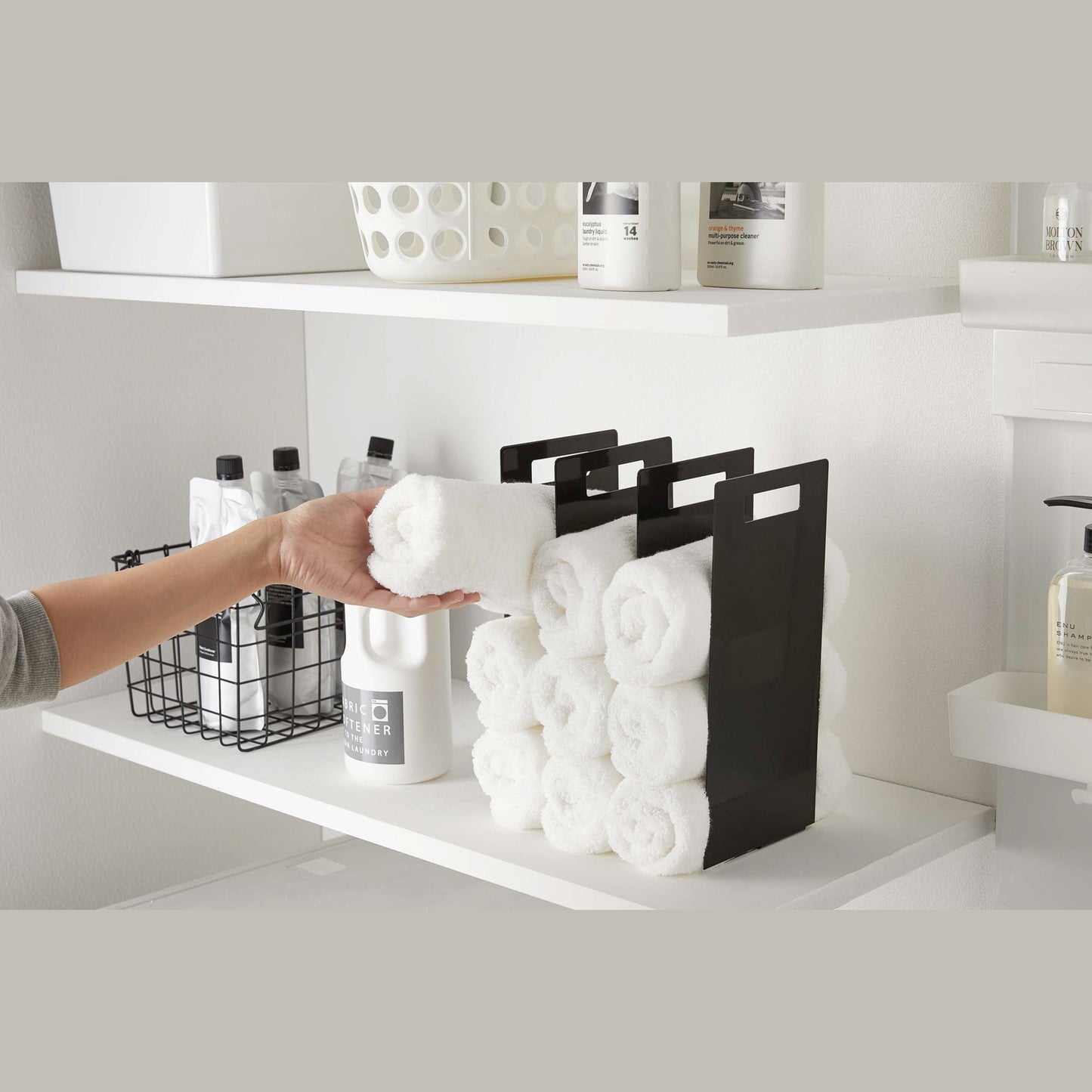 Black Towel Storage Organizer displaying towels in laundry room by Yamazaki Home.