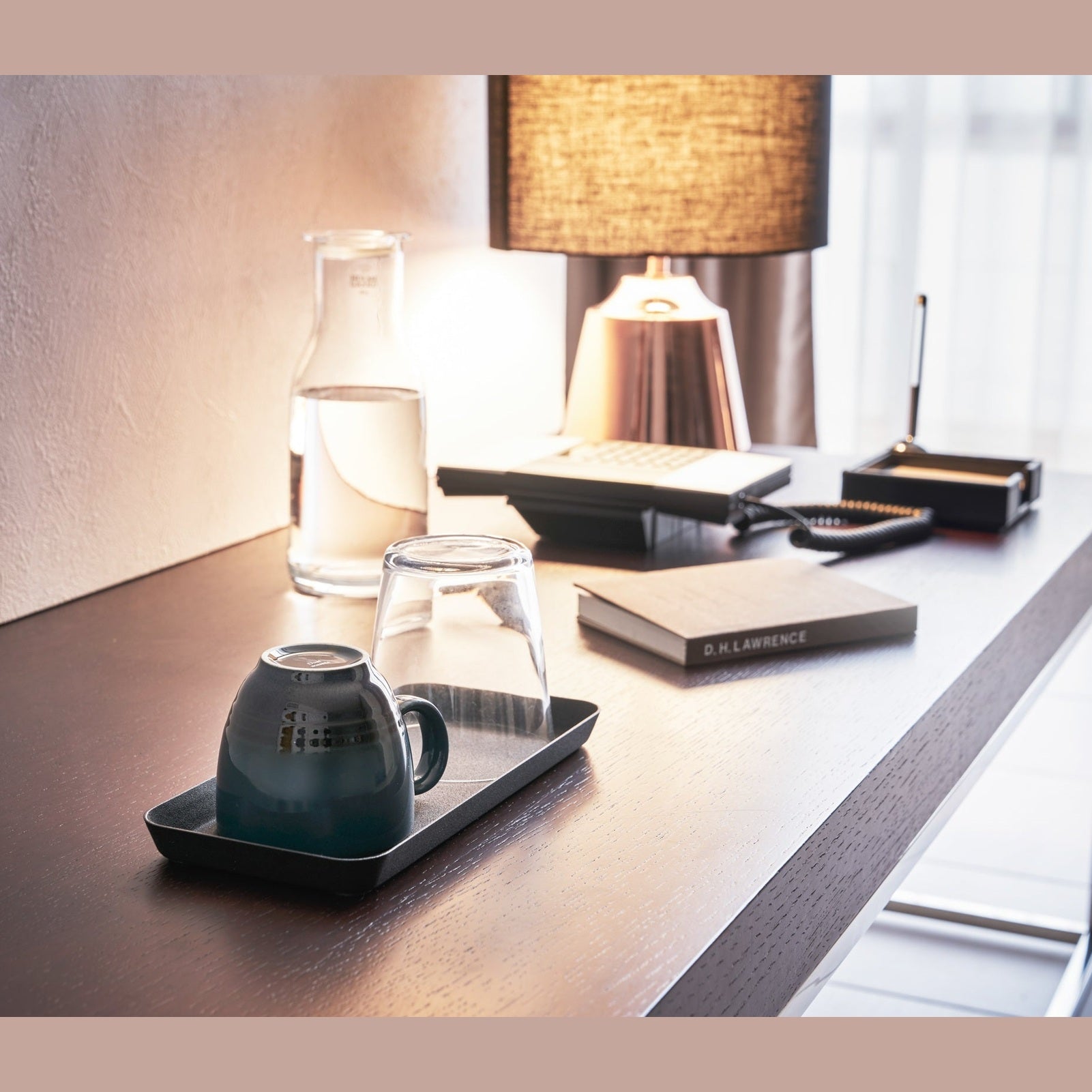 Black Accessory Tray holding mug and glass on desk by Yamazaki Home.