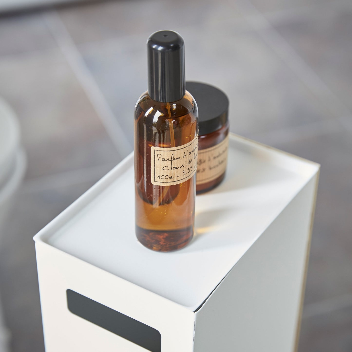 Close up view of white Toilet Paper Stocker displaying perfume bottles by Yamazaki Home.