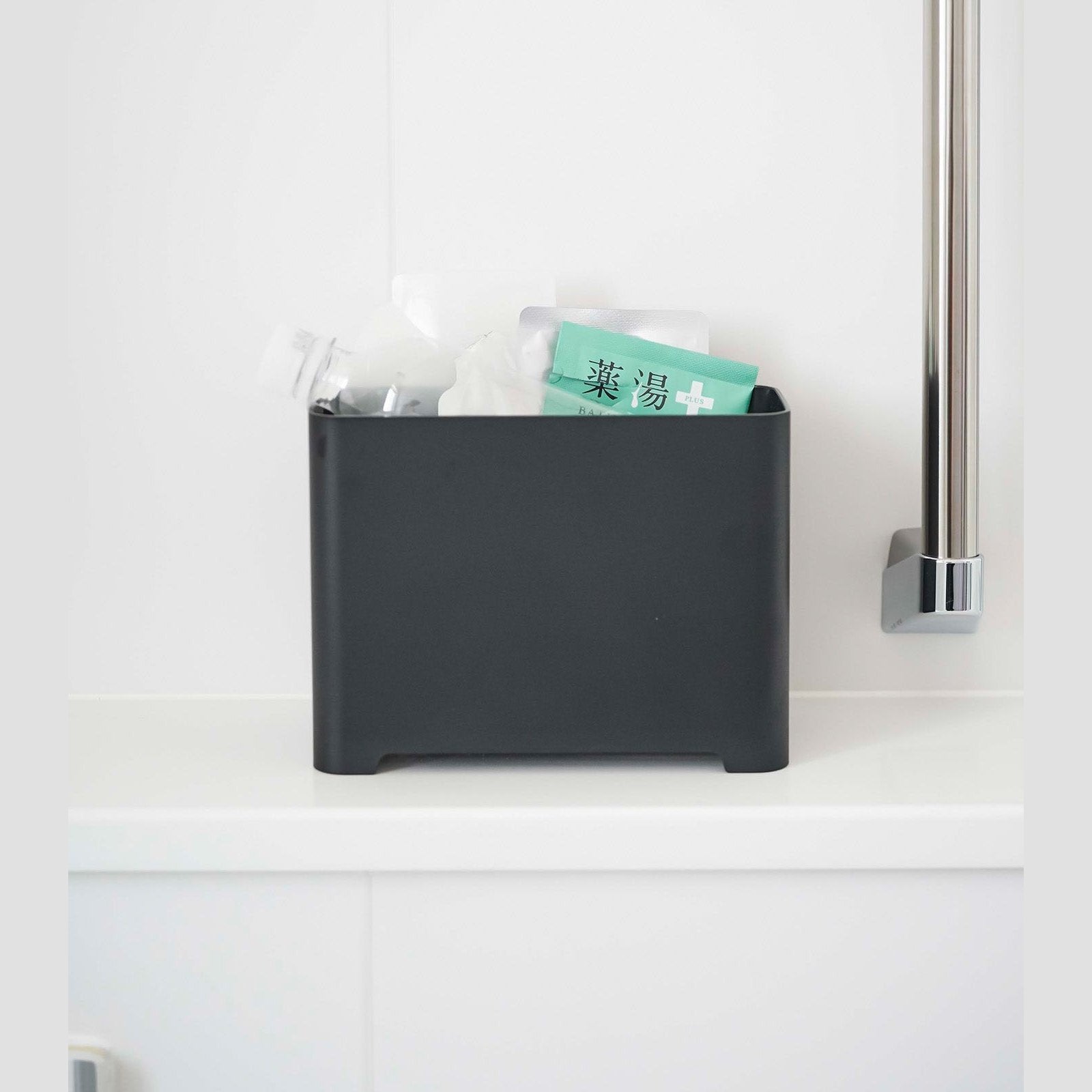 Frontal view of black Yamazaki Self-Draining Bathroom Organizer filled with bath supplies
