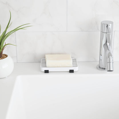 Front view of White Slotted Soap Tray holding soap bar on bathroom countertop by Yamazaki Home.