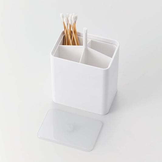 Cotton Swab Push-Top Case in white from Yamazaki Home with Qtips in one of 4 compartments. The semi-transulsent cap is popped off for easy refilling.
