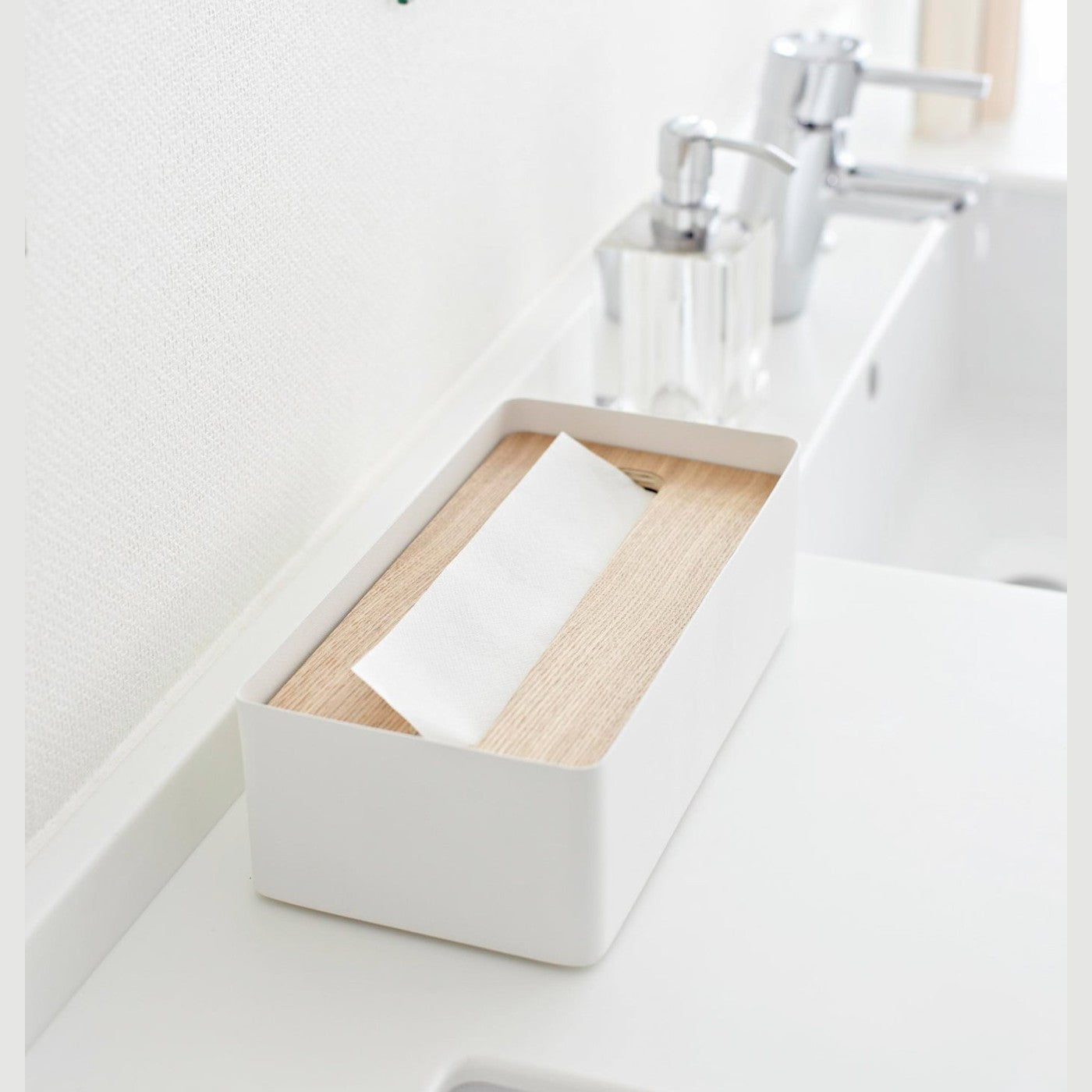 Aerial side view of white Tissue Case on bathroom sink counter by Yamazaki Home.