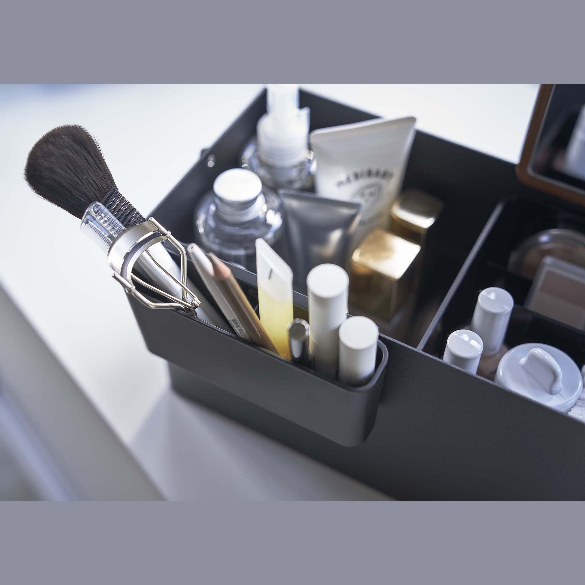 Close up aerial view of black Makeup Organizer containing makeup products by Yamazaki Home.