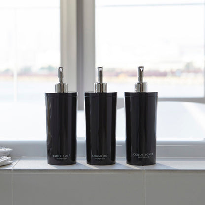 Front view of Yamazaki Home black Shampoo, Conditioner, and Body Soap dispensers in bathroom.