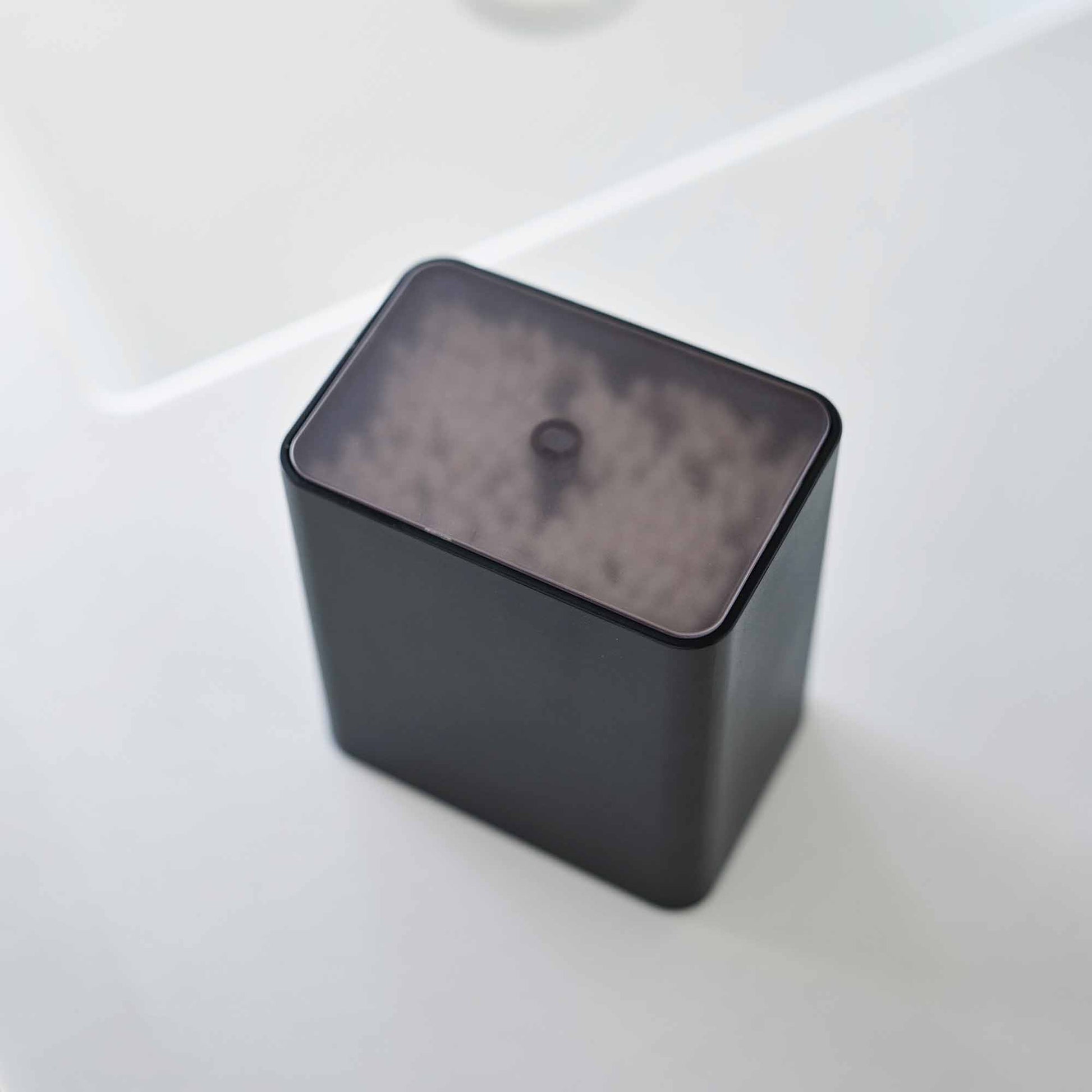 Top view of the cotton swab push-top case with the lid on from Yamazaki Home in black.