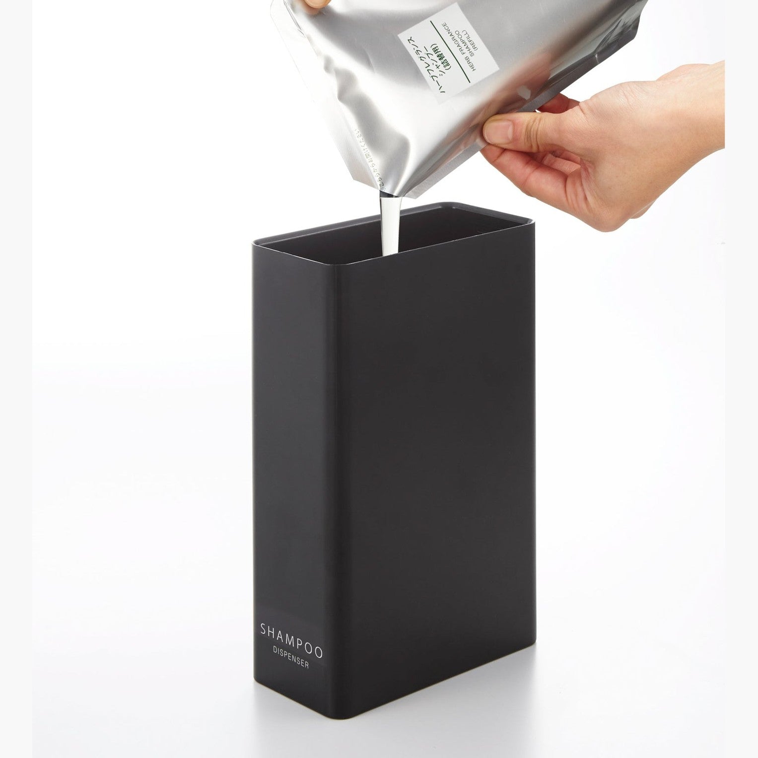 Black Shampoo Dispenser getting filled with shampoo on white background by Yamazaki Home.