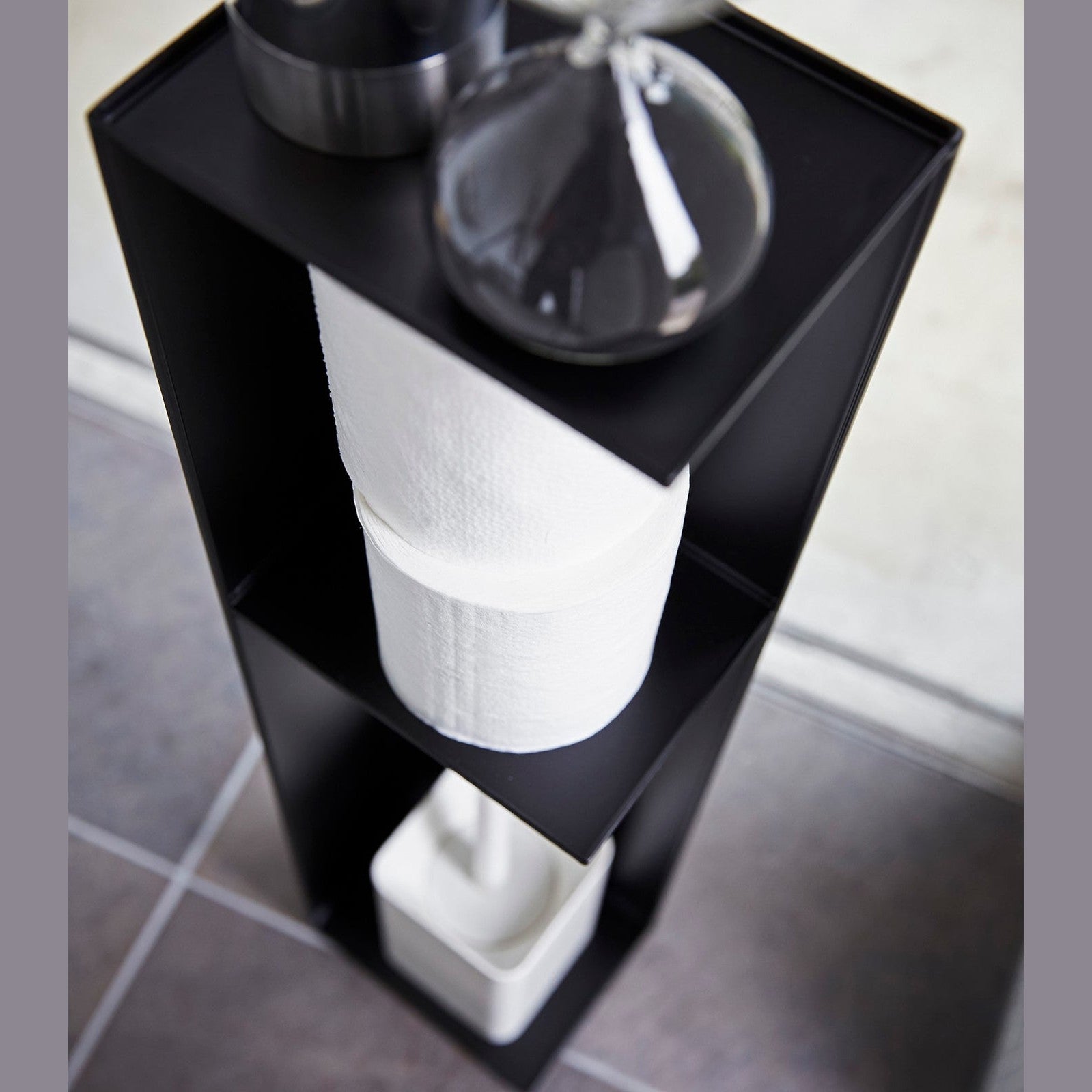 Yamazaki Home black Toilet Organizer holding decor pieces, toilet paper, and toilet brush.